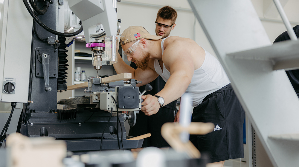 Zwei Studenten arbeiten an einer Maschine in der StudierendenWerkstatt (c) Jana Dünnhaupt Uni Magdeburg