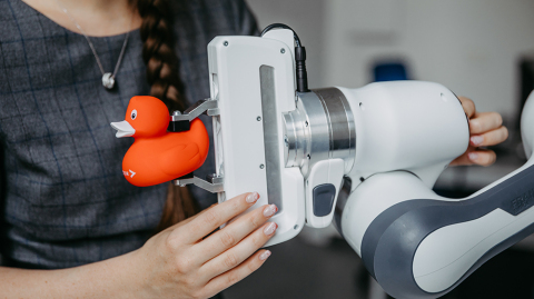 Der Roboterarm hält eine Gummiente